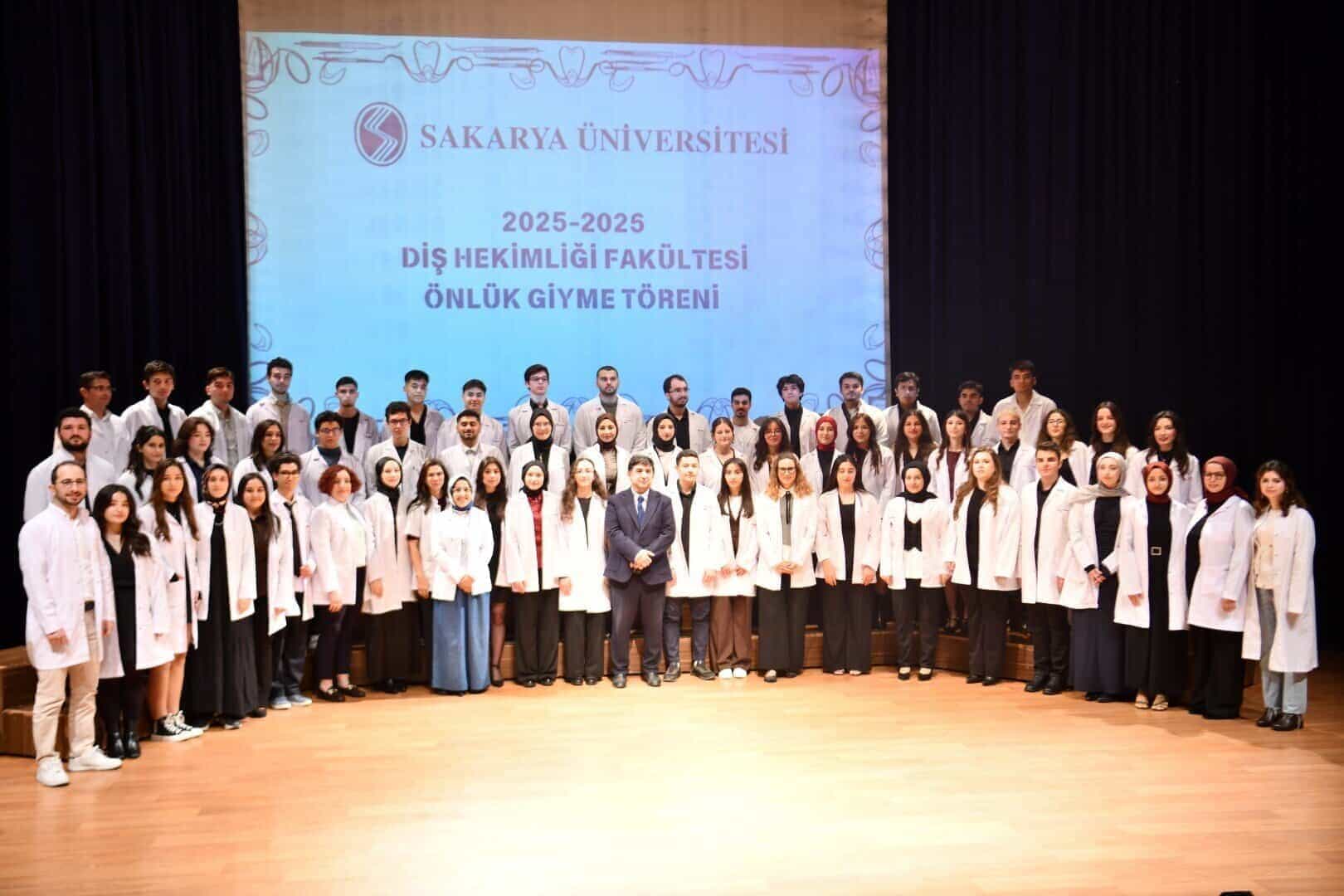 Diş hekimliği öğrencileri tören kıyafetleriyle sahnede.